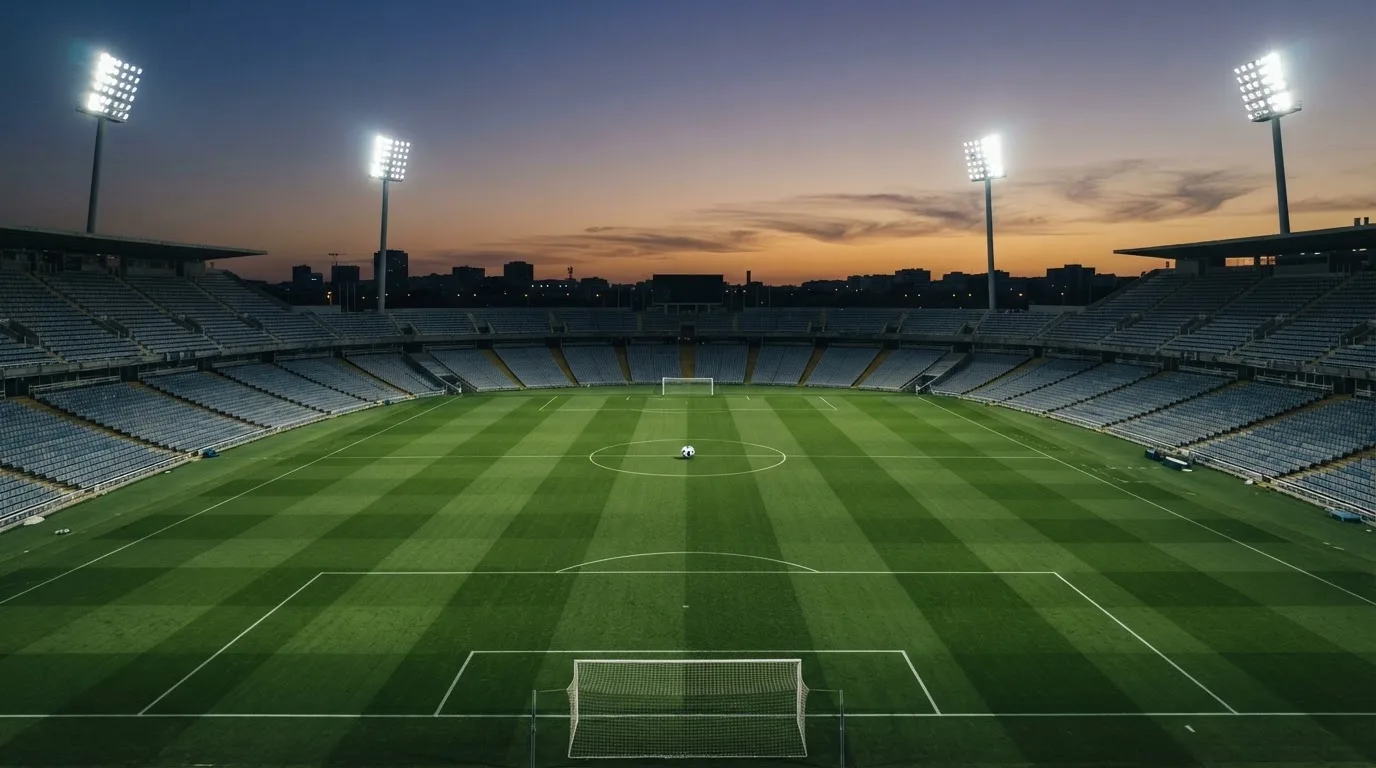 An empty football stadium with floodlight masts at dusk