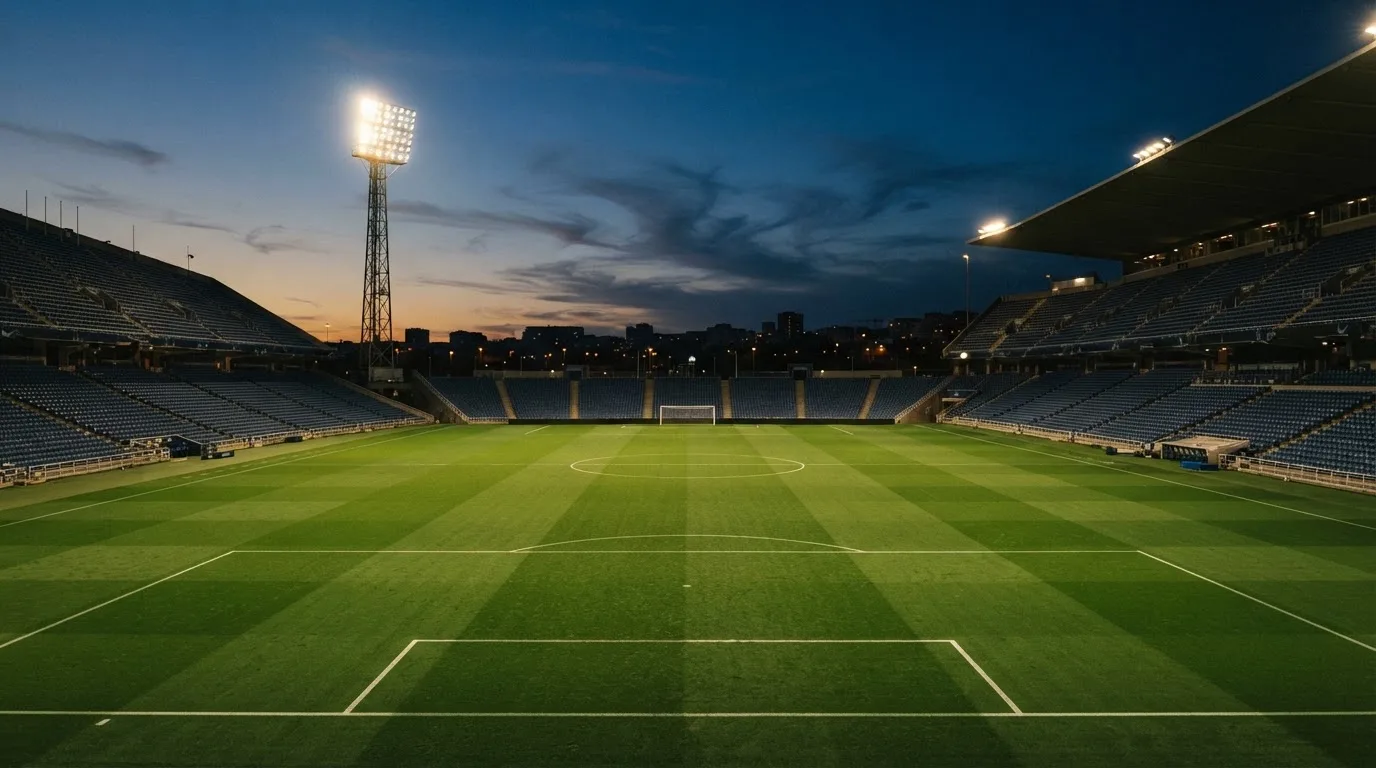 An empty football stadium with floodlight masts at dusk