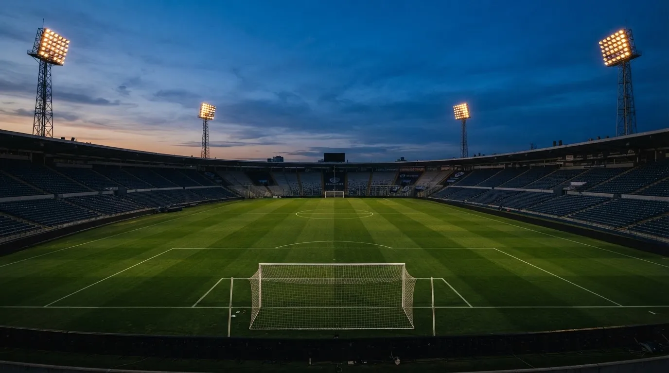 An empty football stadium with floodlight masts at dusk