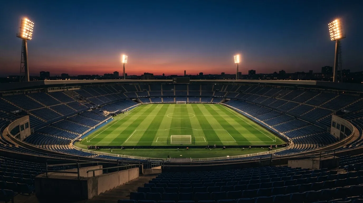 An empty football stadium with floodlight masts at dusk