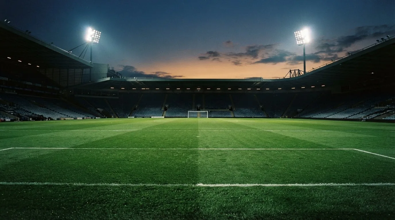 An empty football stadium with floodlight masts at dusk