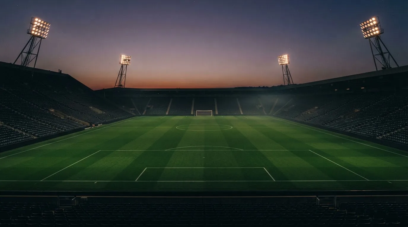 An empty football stadium with floodlight masts at dusk