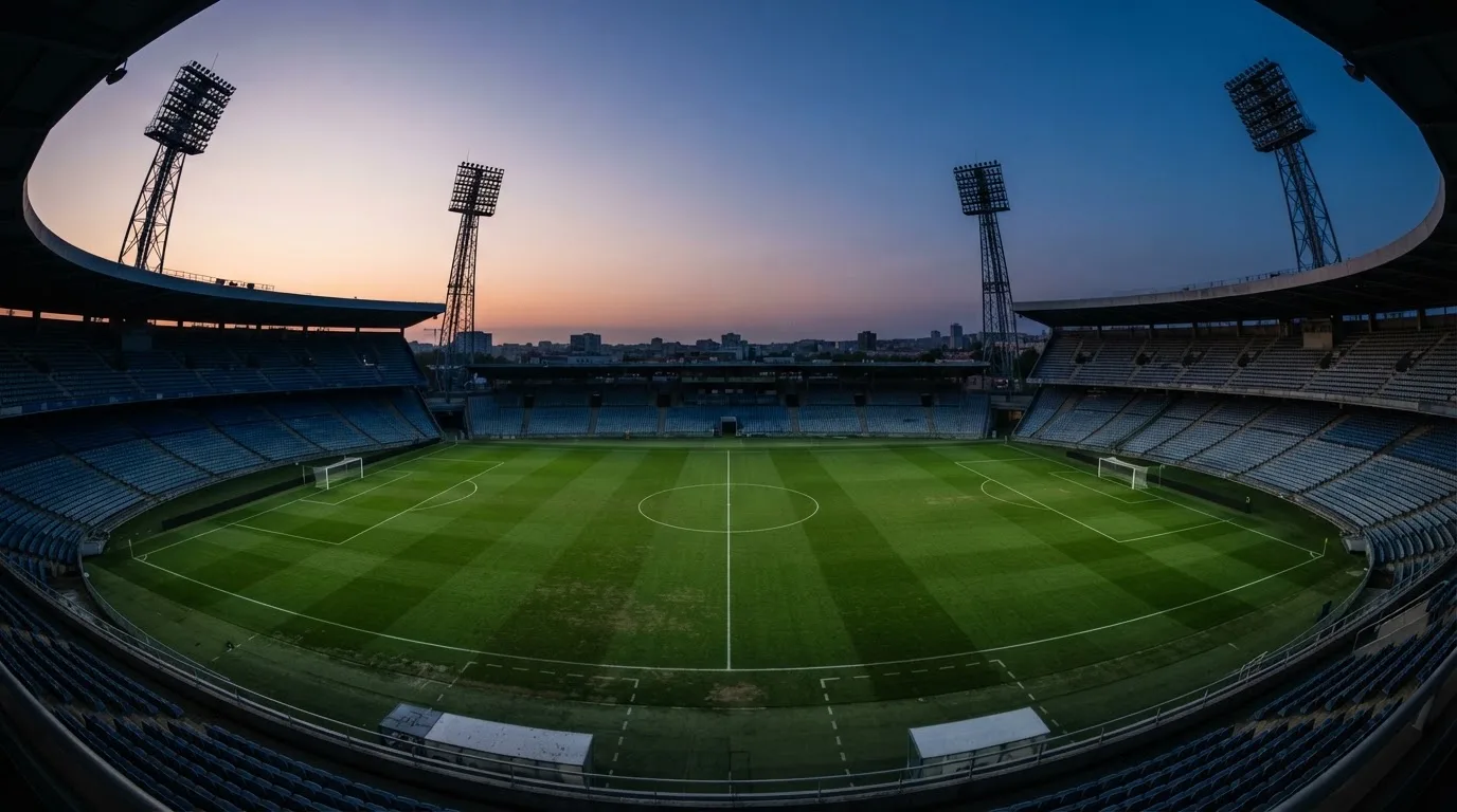 An empty football stadium with floodlight masts at dusk