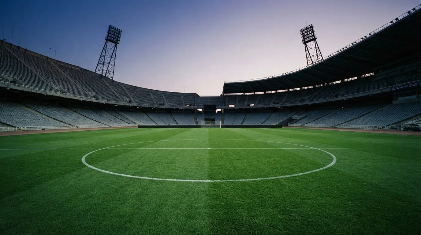 An empty football stadium with floodlight masts at dusk