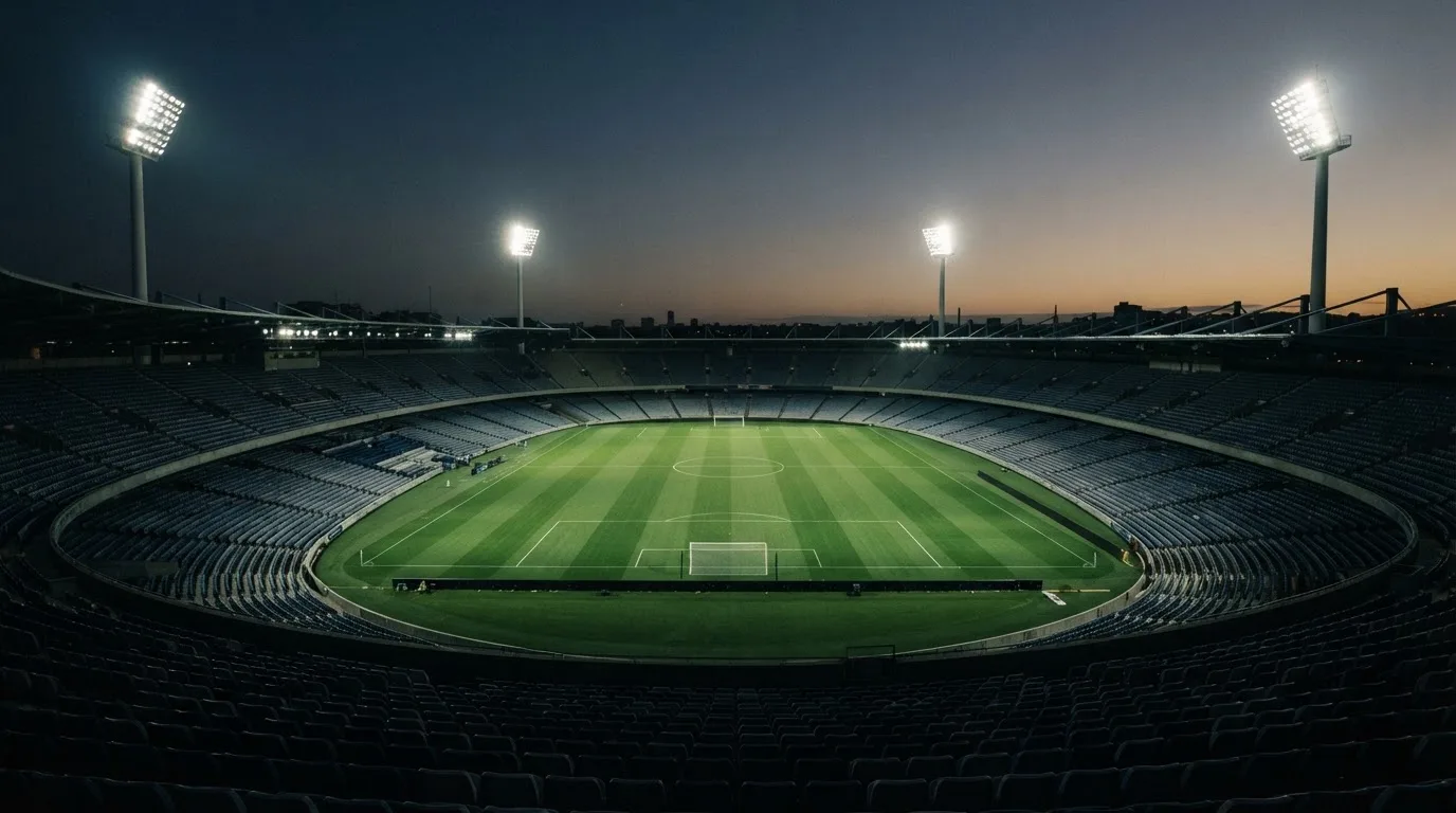 An empty football stadium with floodlight masts at dusk