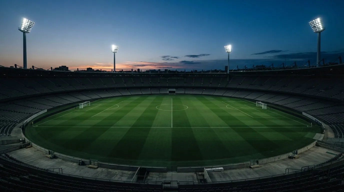 An empty football stadium with floodlight masts at dusk