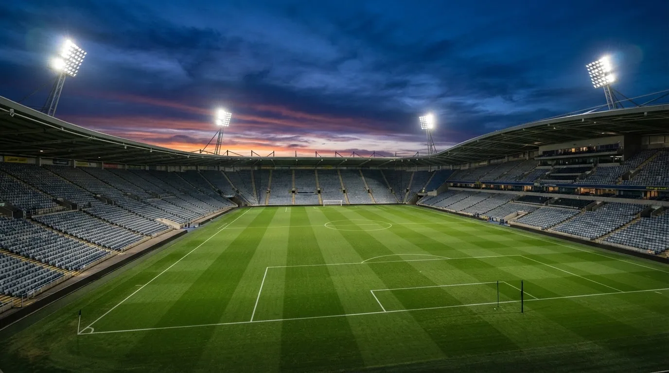 An empty football stadium with floodlight masts at dusk