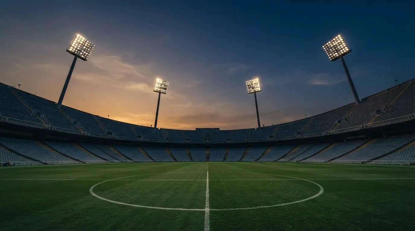 An empty football stadium with floodlight masts at dusk