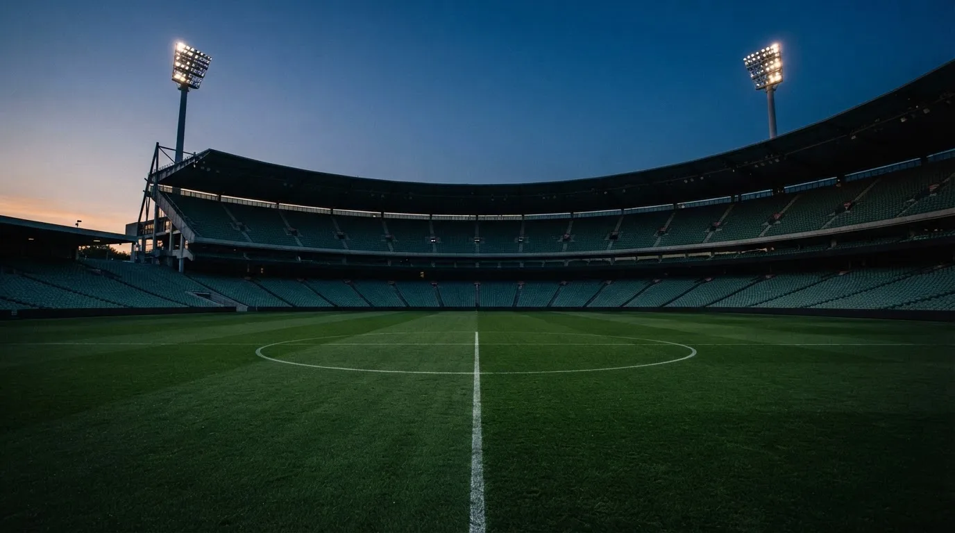 An empty football stadium with floodlight masts at dusk