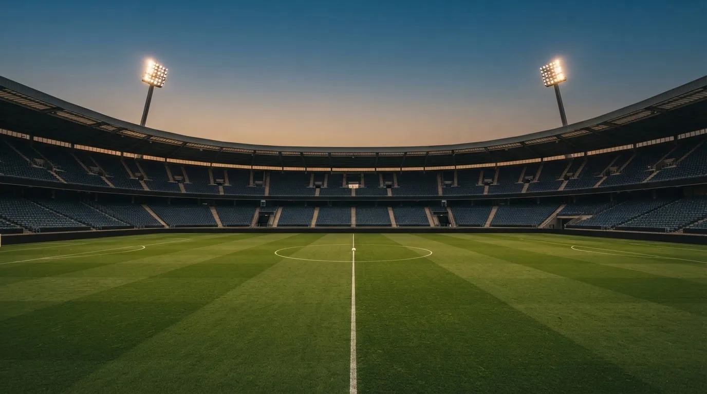 An empty football stadium with floodlight masts at dusk