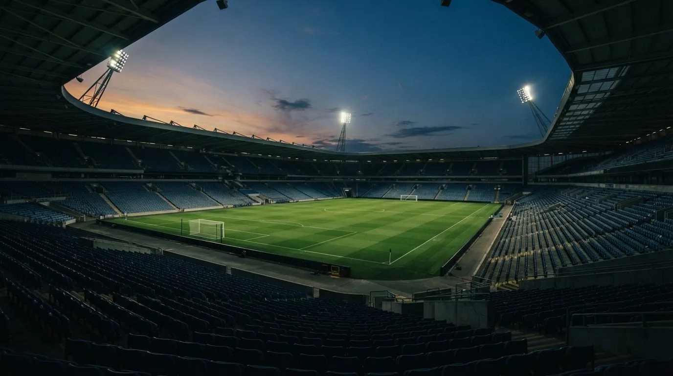 An empty football stadium with floodlight masts at dusk