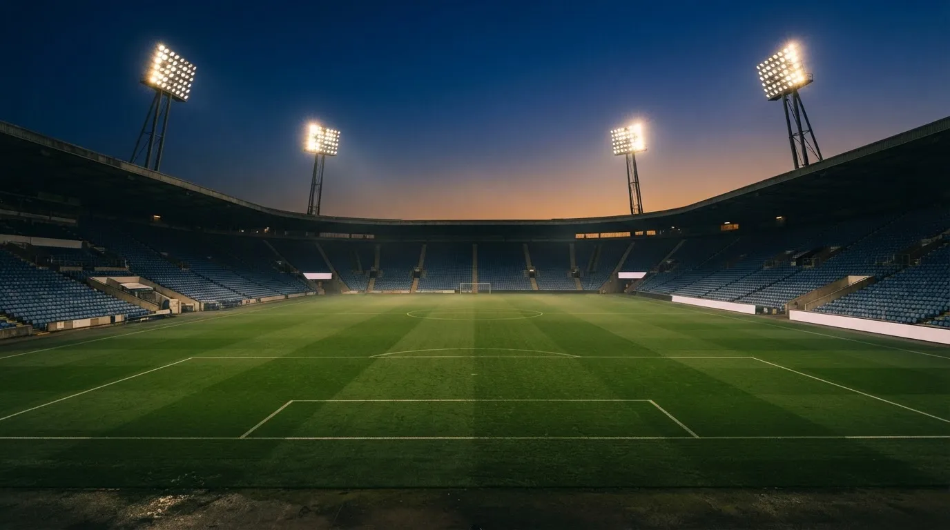 An empty football stadium with floodlight masts at dusk