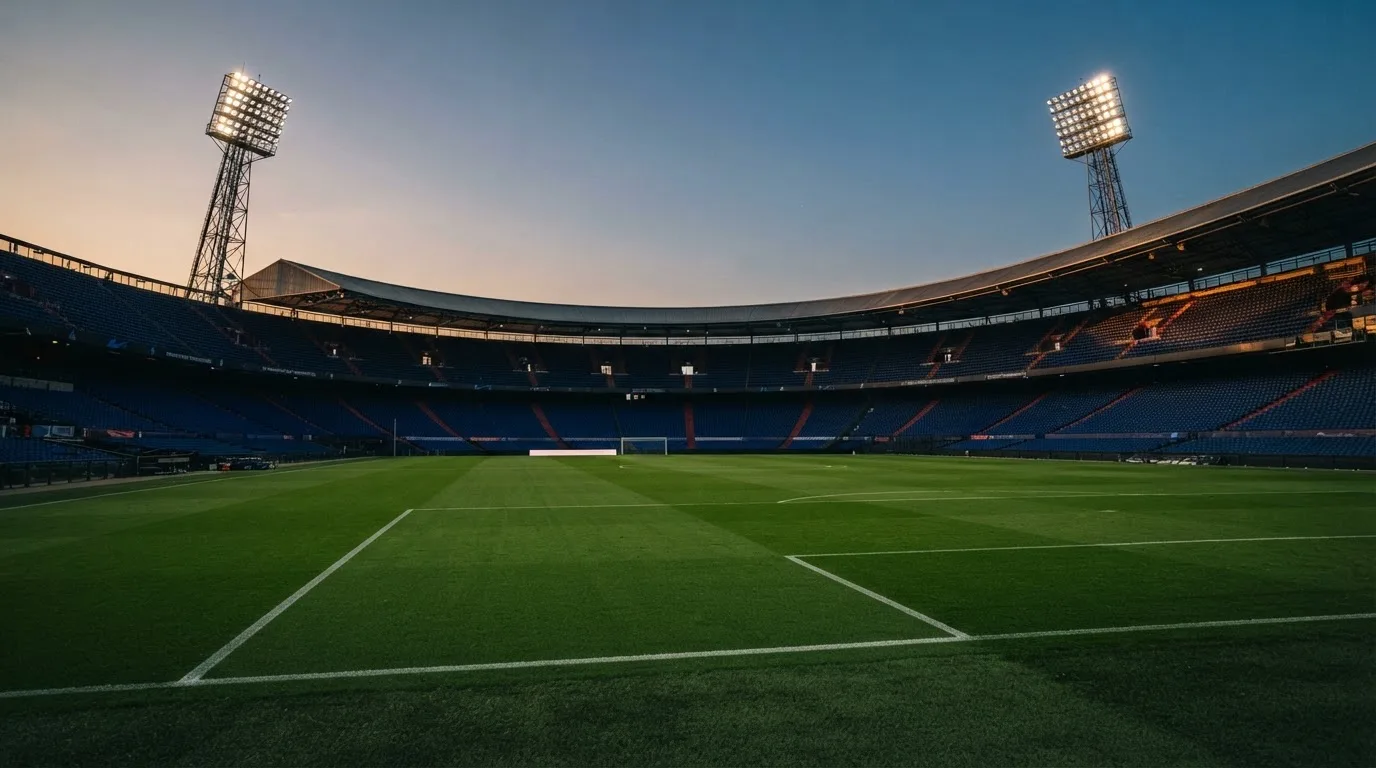 An empty football stadium with floodlight masts at dusk