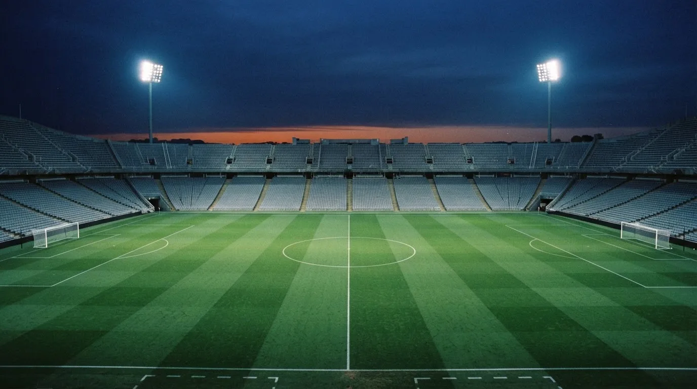 An empty football stadium with floodlight masts at dusk