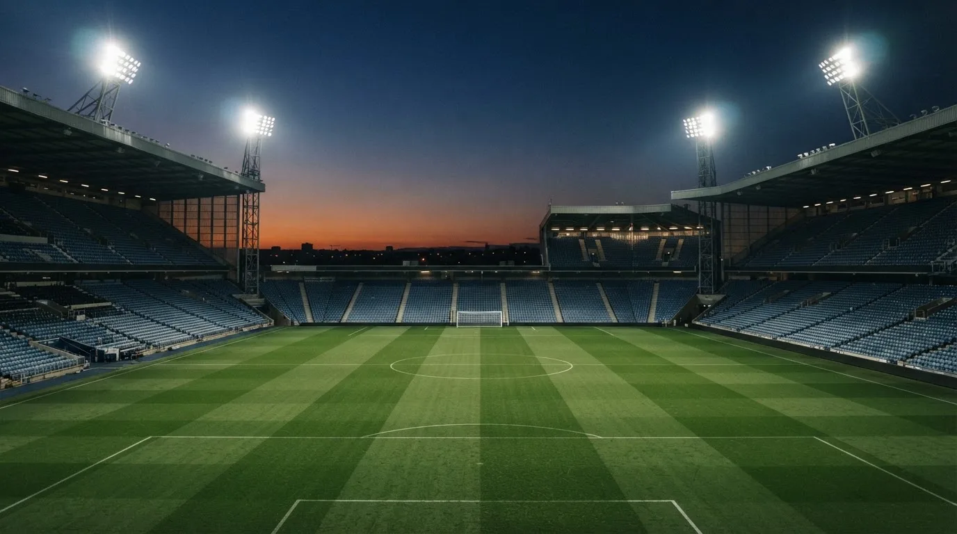 An empty football stadium with floodlight masts at dusk