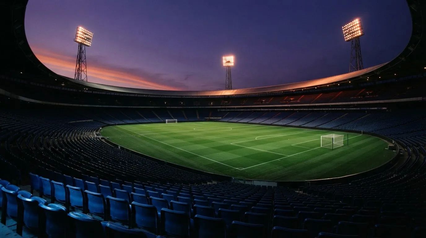 An empty football stadium with floodlight masts at dusk