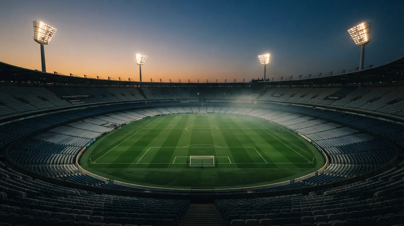 An empty football stadium with floodlight masts at dusk