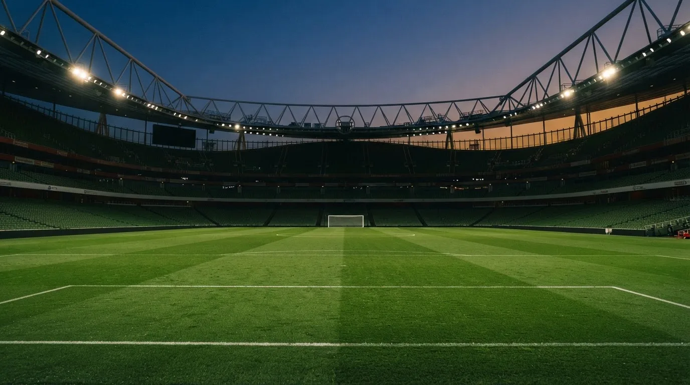 An empty football stadium with floodlight masts at dusk