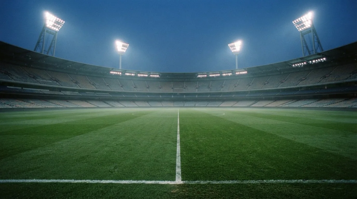 An empty football stadium with floodlight masts at dusk
