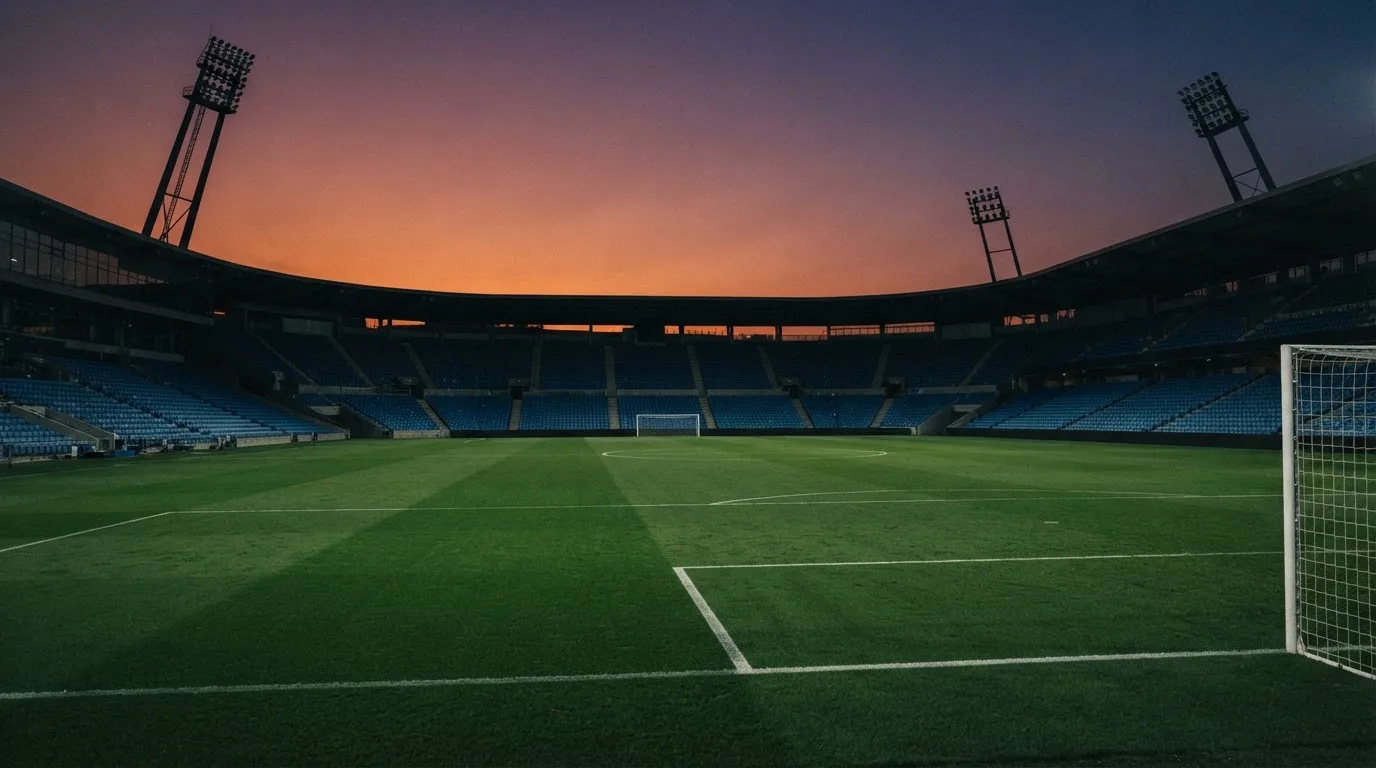 An empty football stadium with floodlight masts at dusk