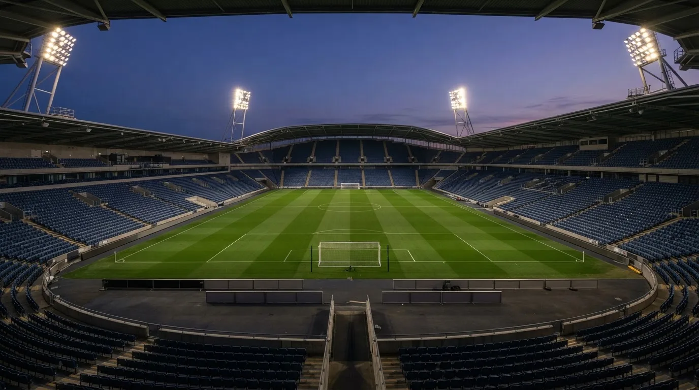 An empty football stadium with floodlight masts at dusk