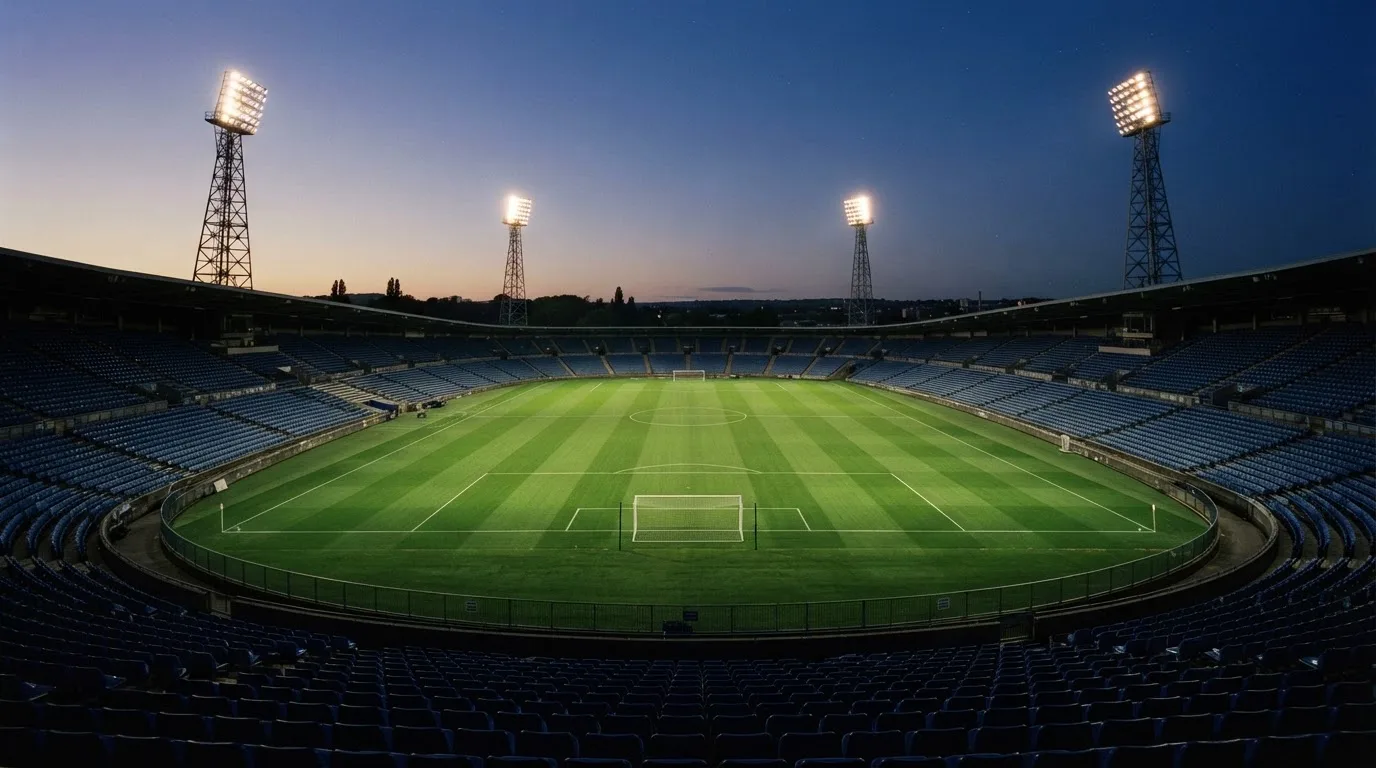 An empty football stadium with floodlight masts at dusk