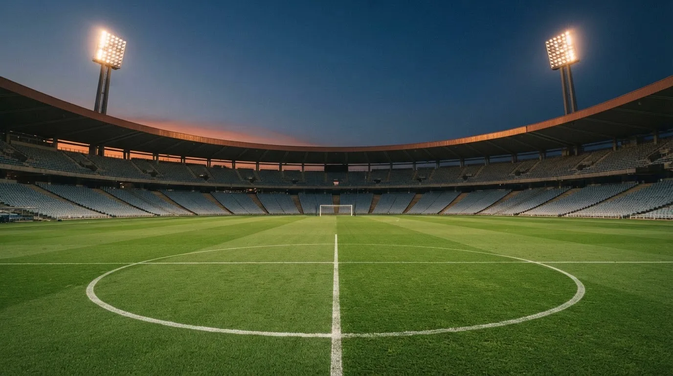 An empty football stadium with floodlight masts at dusk