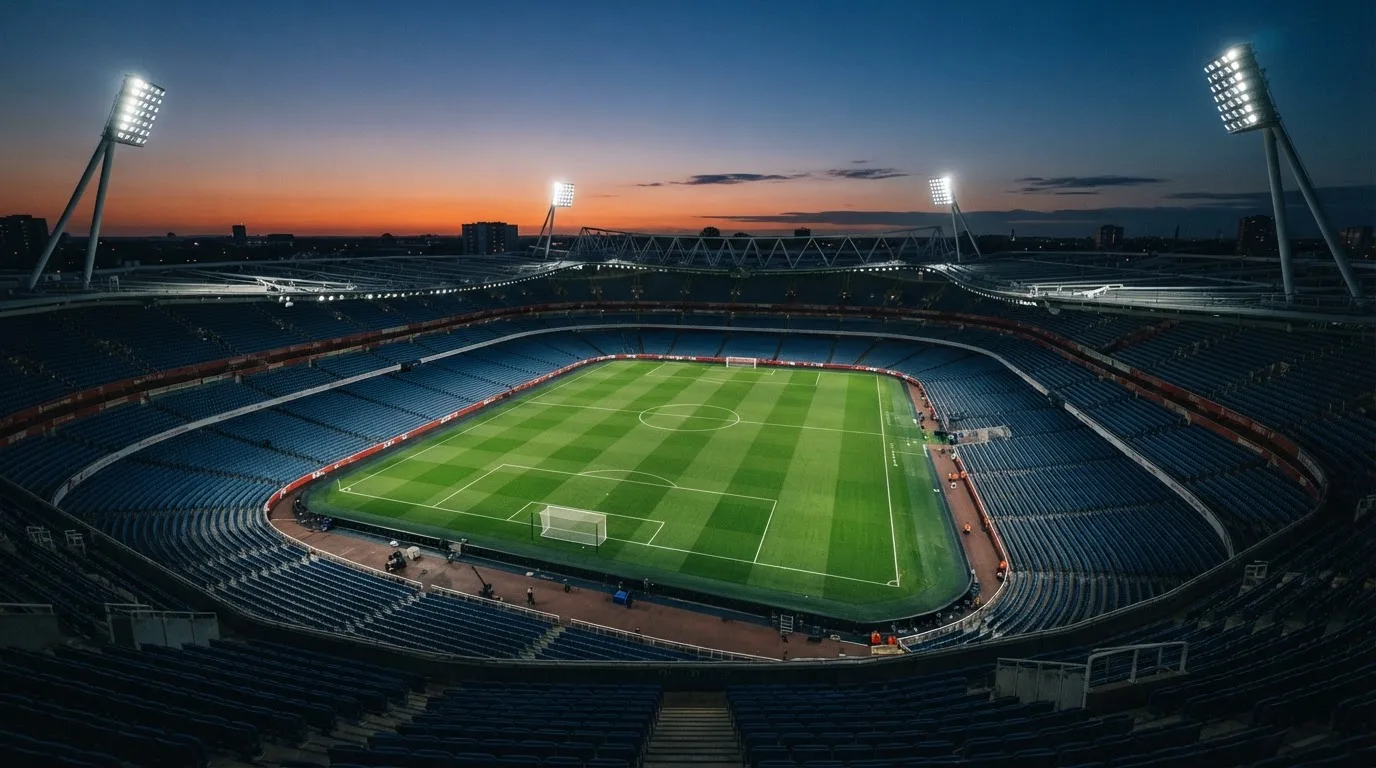 An empty football stadium with floodlight masts at dusk