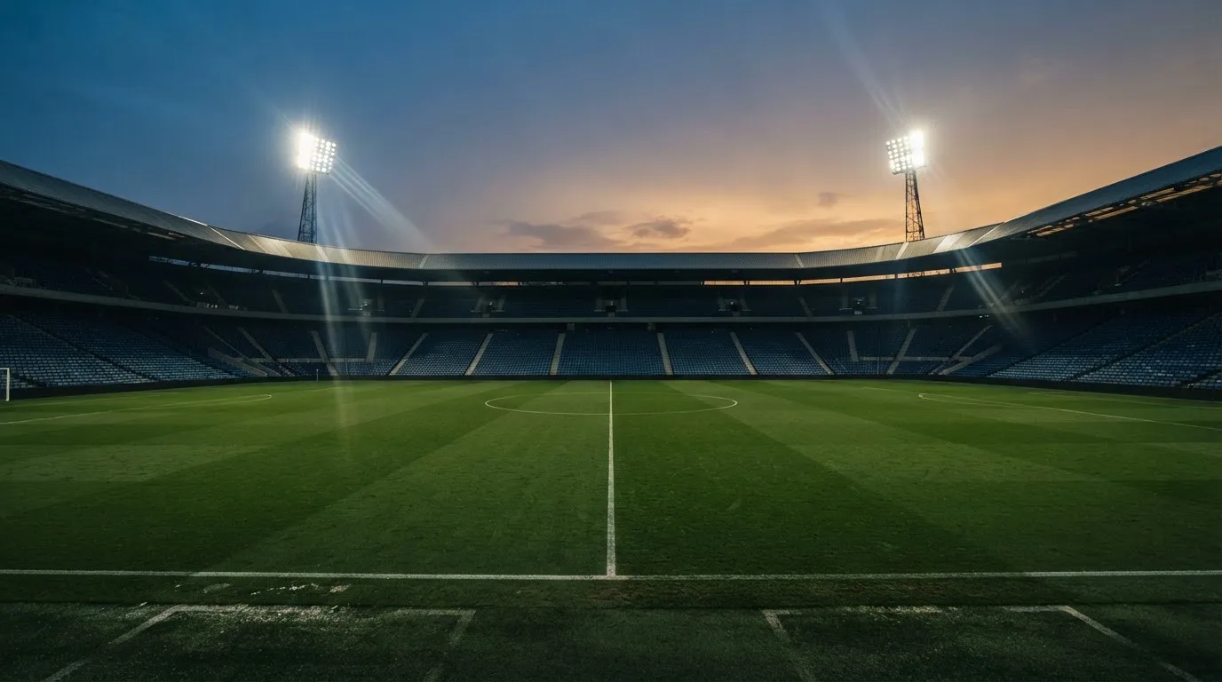 An empty football stadium with floodlight masts at dusk