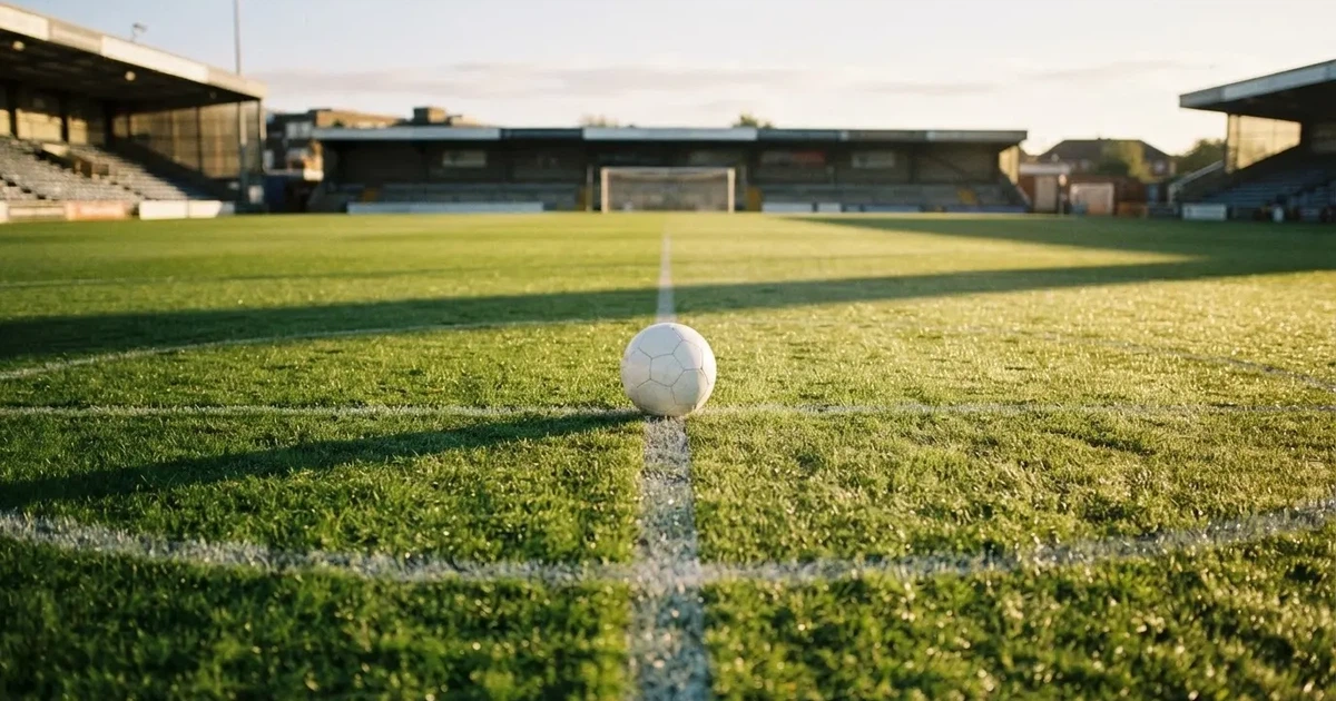 A ball on the centre spot of a grass pitch in morning light