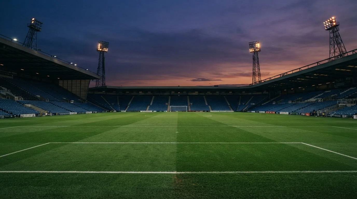 An empty football stadium with floodlight masts at dusk