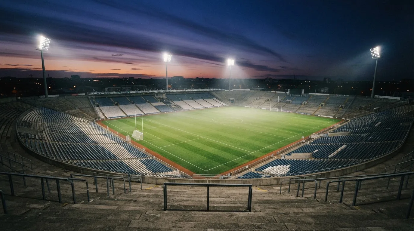 An empty football stadium with floodlight masts at dusk