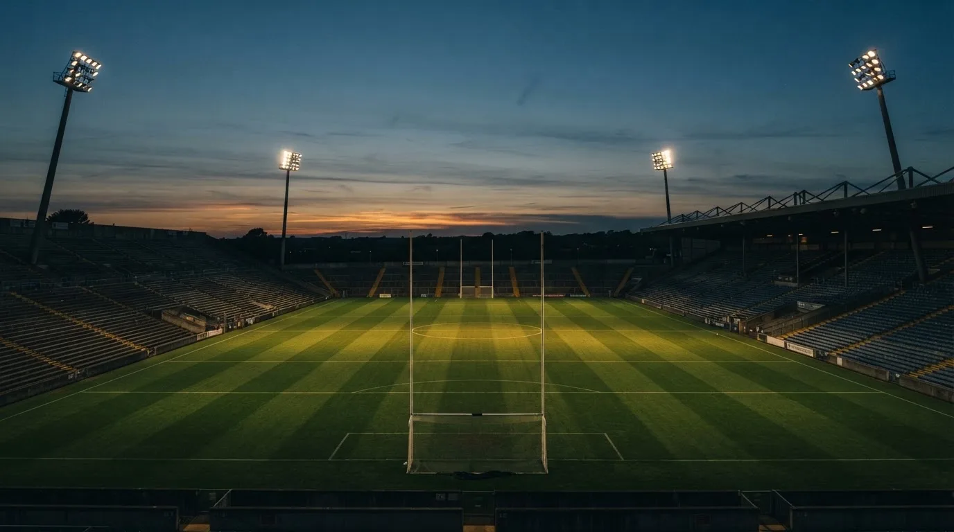 An empty football stadium with floodlight masts at dusk