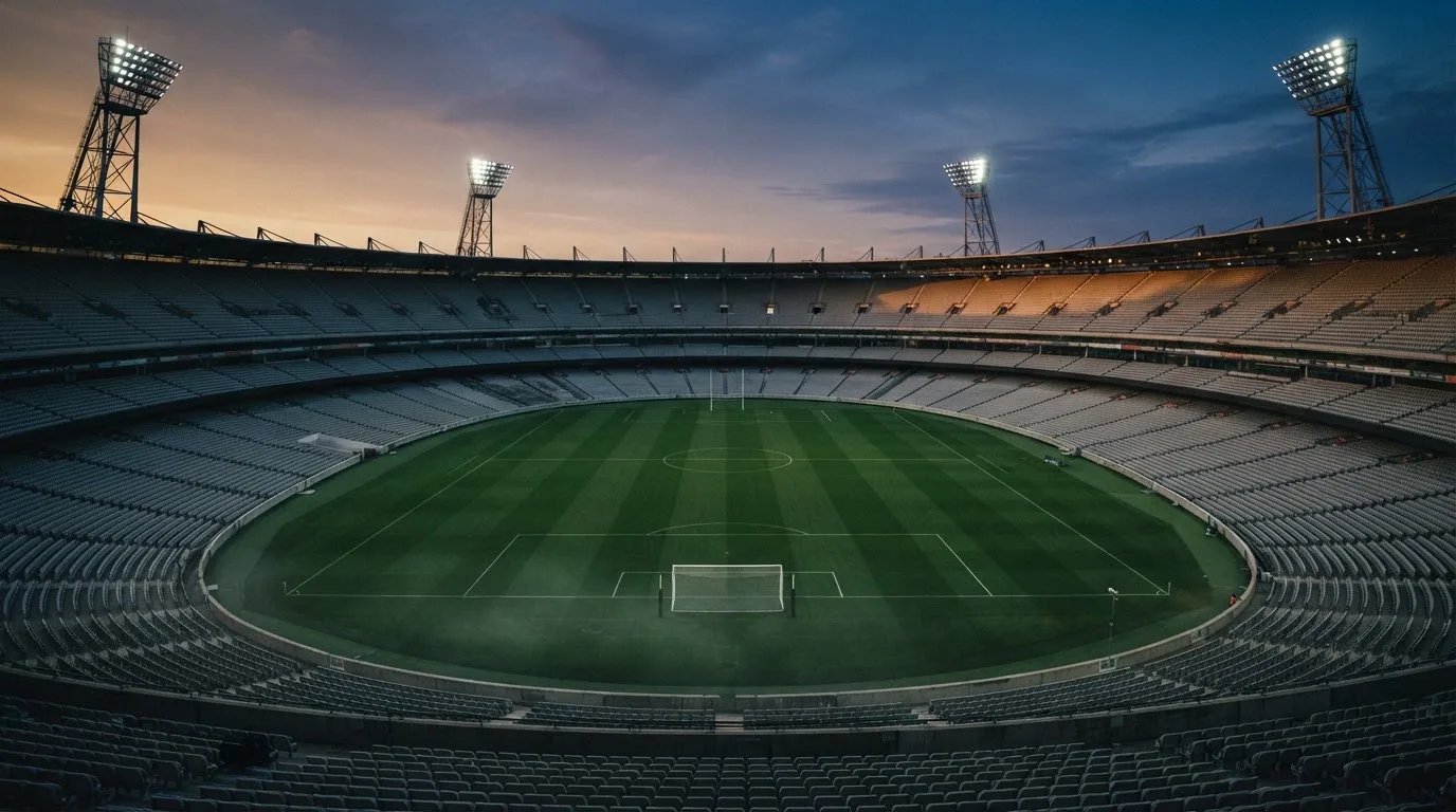 An empty football stadium with floodlight masts at dusk