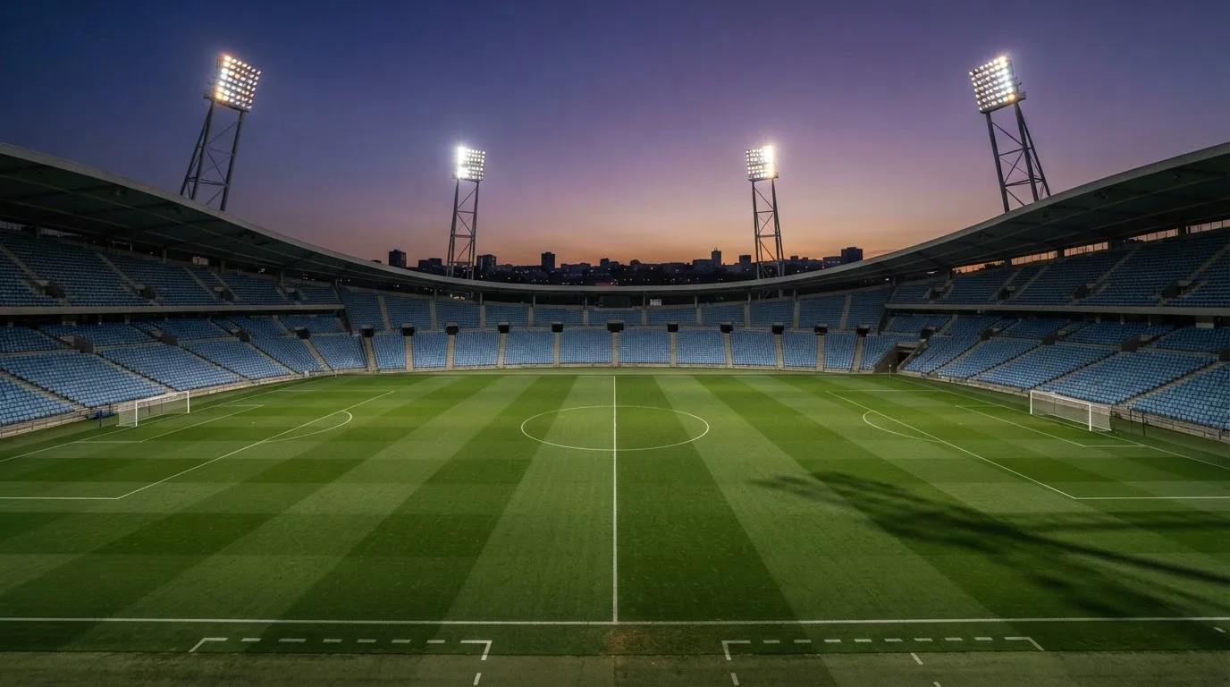 An empty football stadium with floodlight masts at dusk