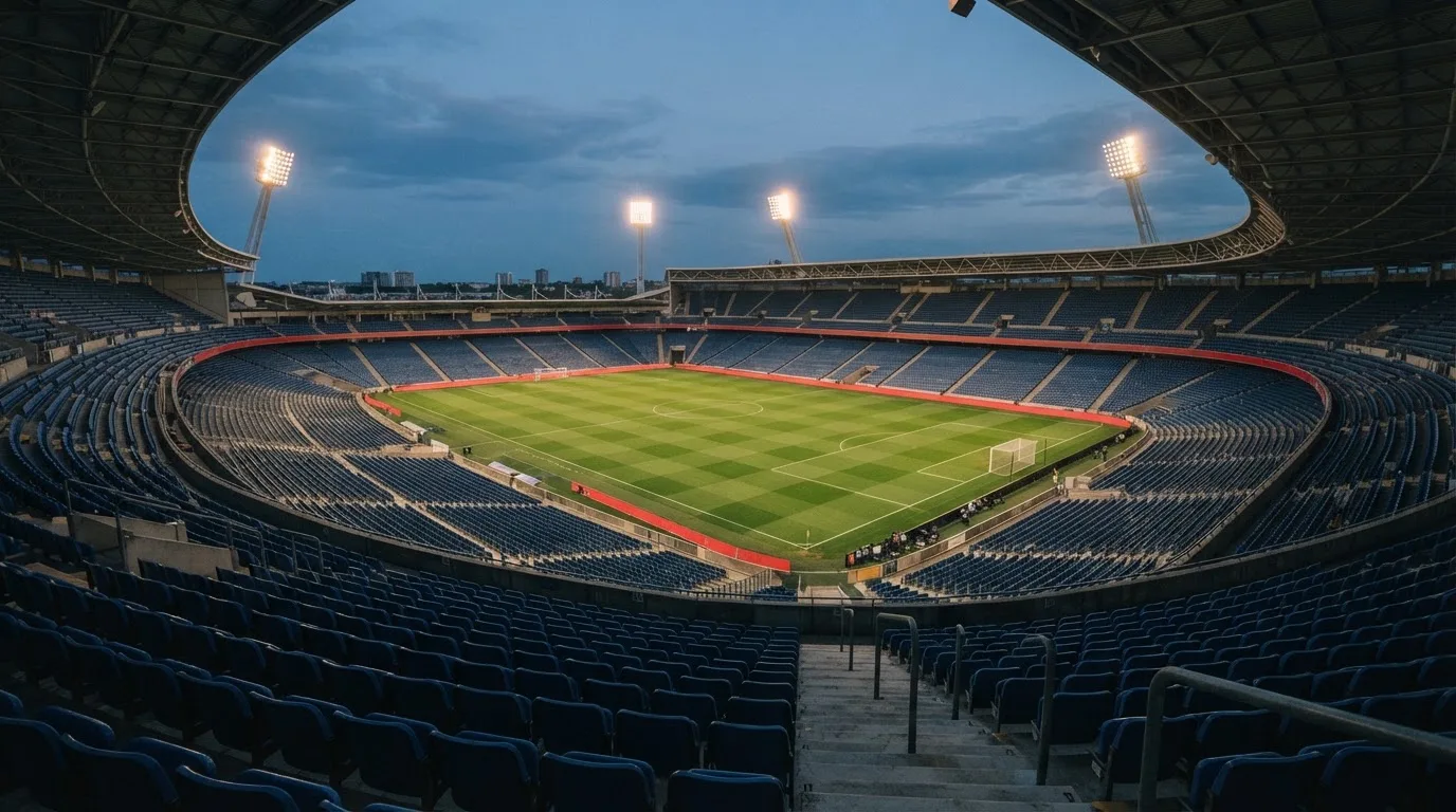 An empty football stadium with floodlight masts at dusk