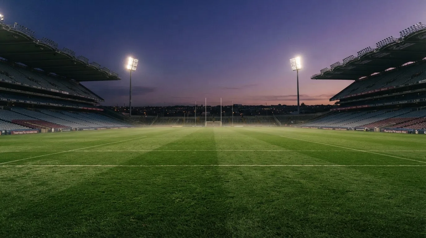 An empty football stadium with floodlight masts at dusk