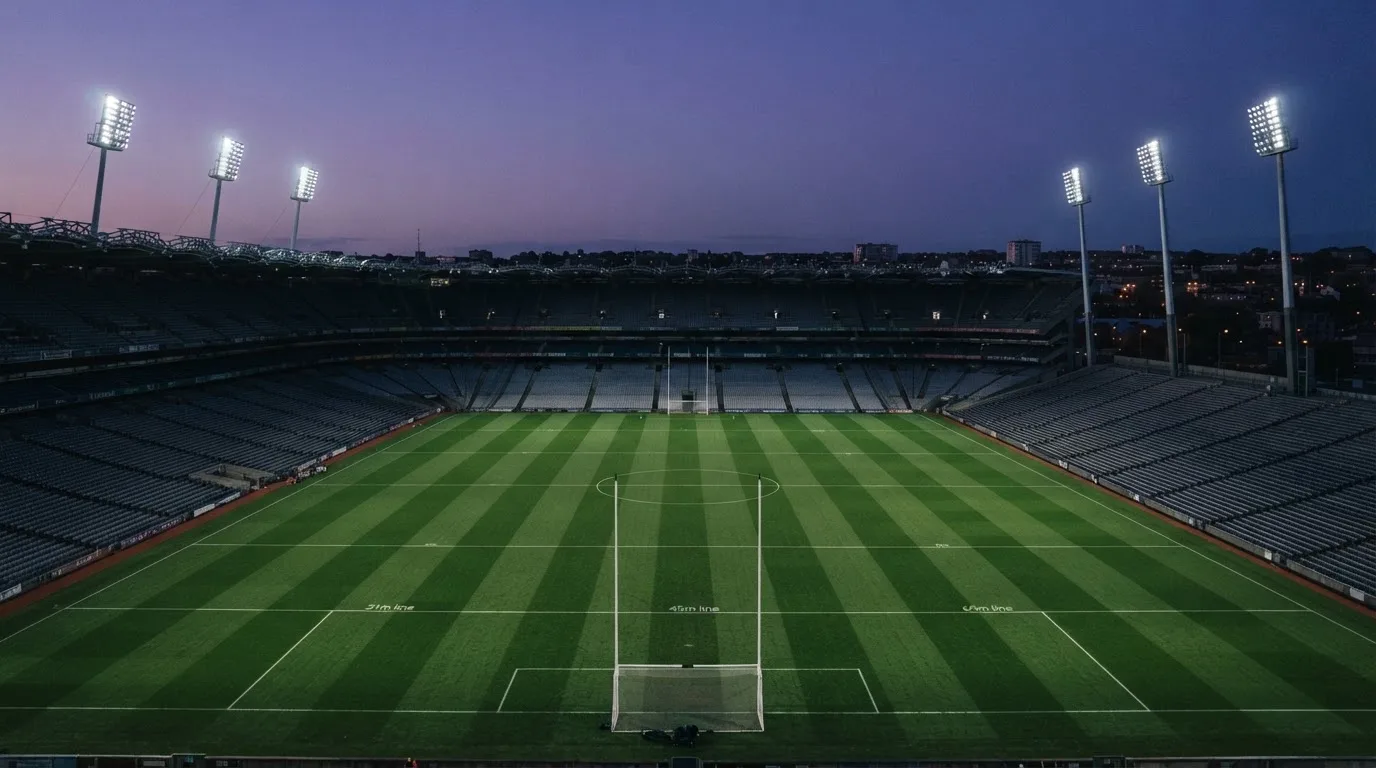 An empty football stadium with floodlight masts at dusk