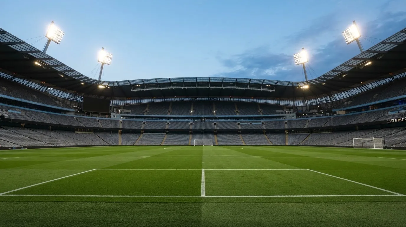 An empty football stadium with floodlight masts at dusk