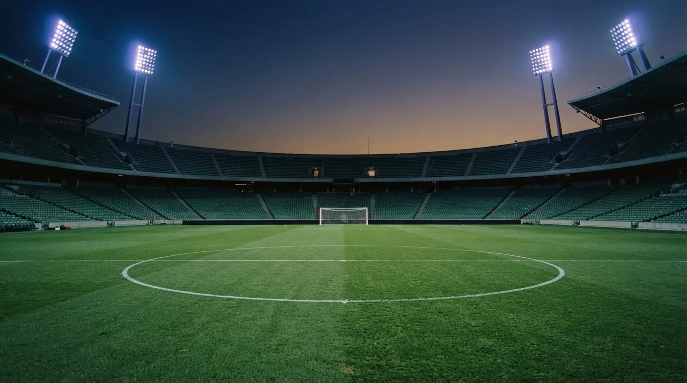An empty football stadium with floodlight masts at dusk