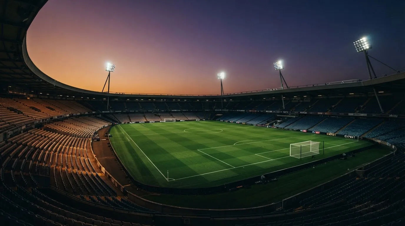 An empty football stadium with floodlight masts at dusk