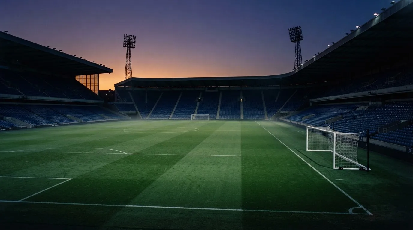 An empty football stadium with floodlight masts at dusk