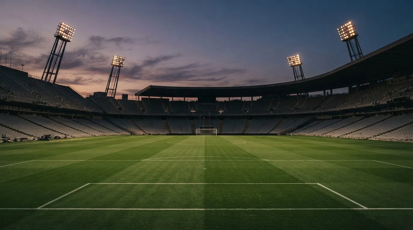 An empty football stadium with floodlight masts at dusk