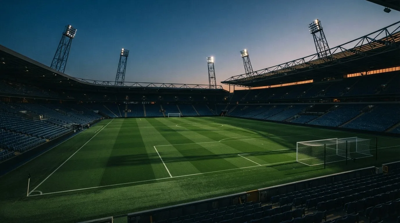 An empty football stadium with floodlight masts at dusk