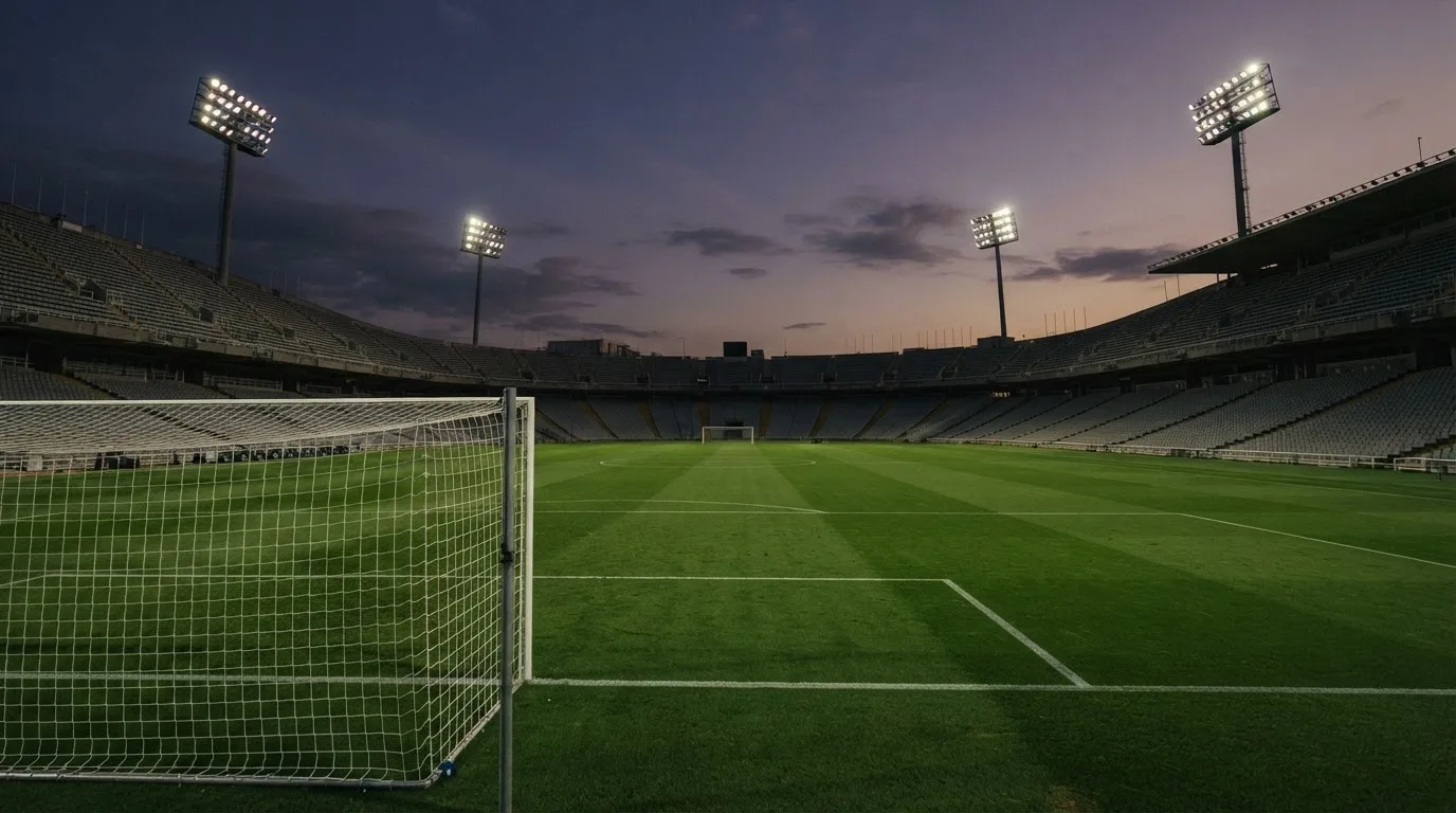 An empty football stadium with floodlight masts at dusk