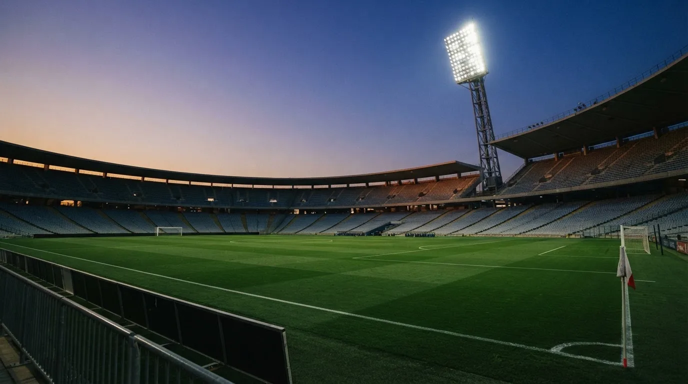 An empty football stadium with floodlight masts at dusk