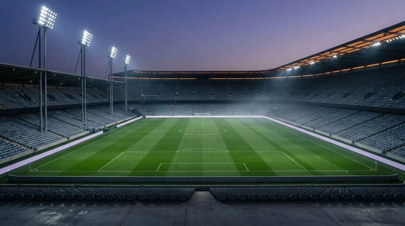 An empty football stadium with floodlight masts at dusk