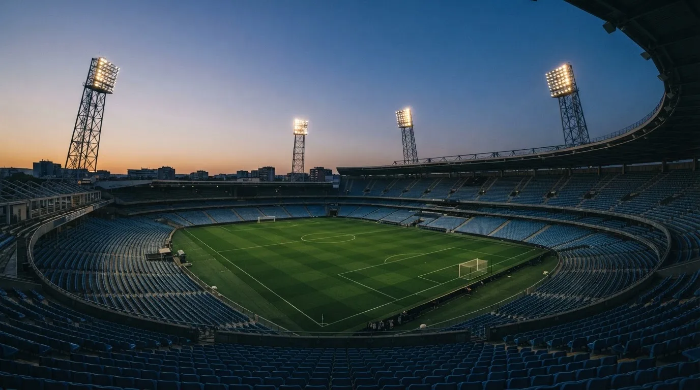 An empty football stadium with floodlight masts at dusk