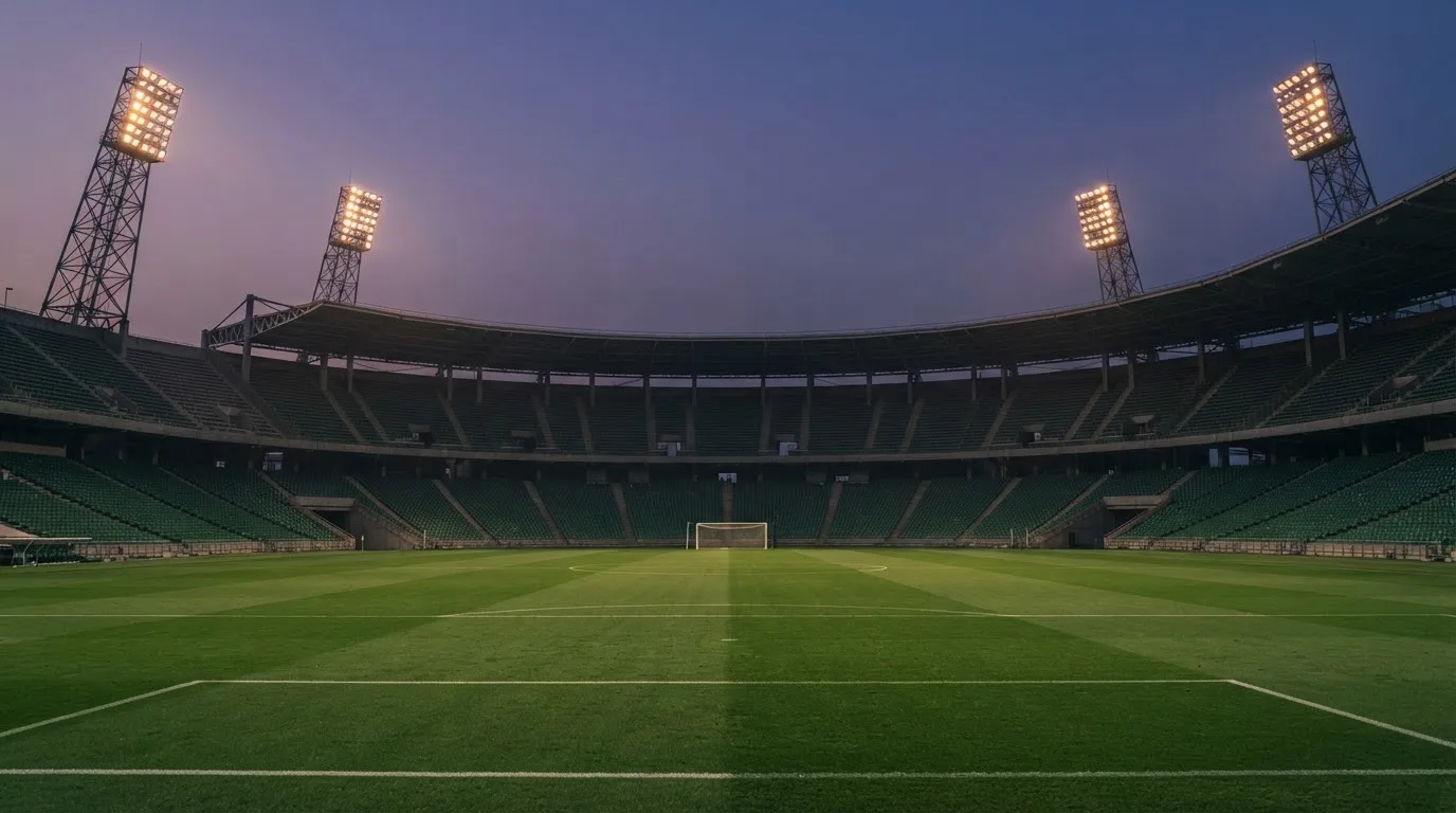 An empty football stadium with floodlight masts at dusk