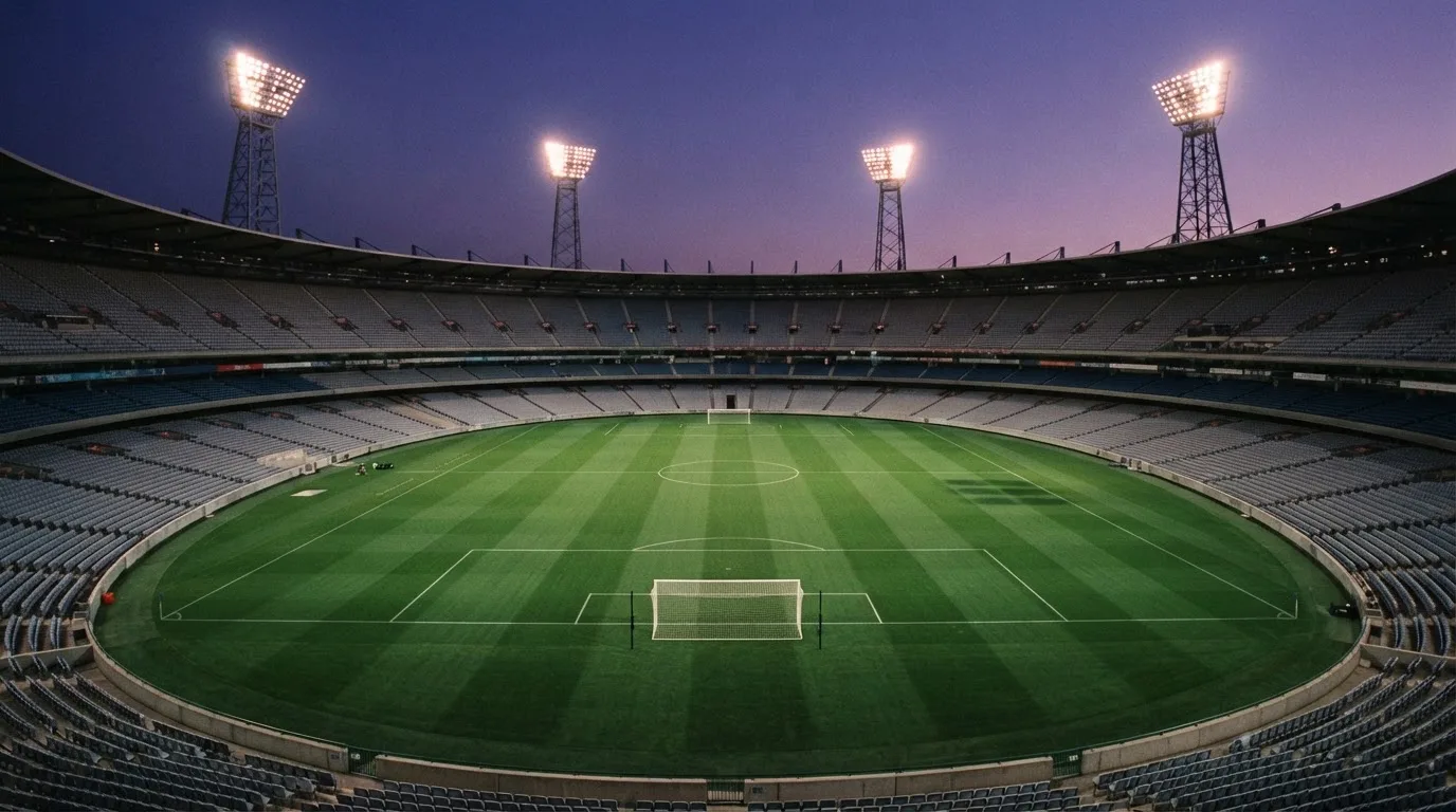 An empty football stadium with floodlight masts at dusk
